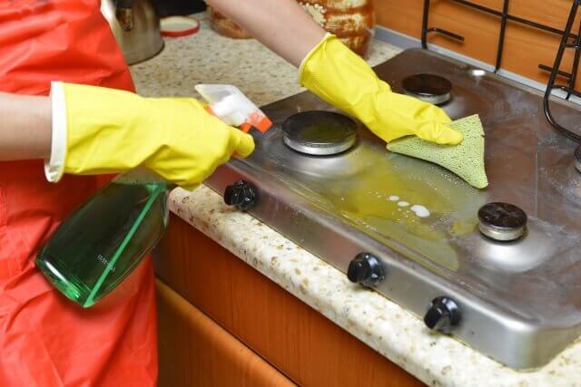 キッチンのガスコンロを綺麗に清掃するスタッフの写真