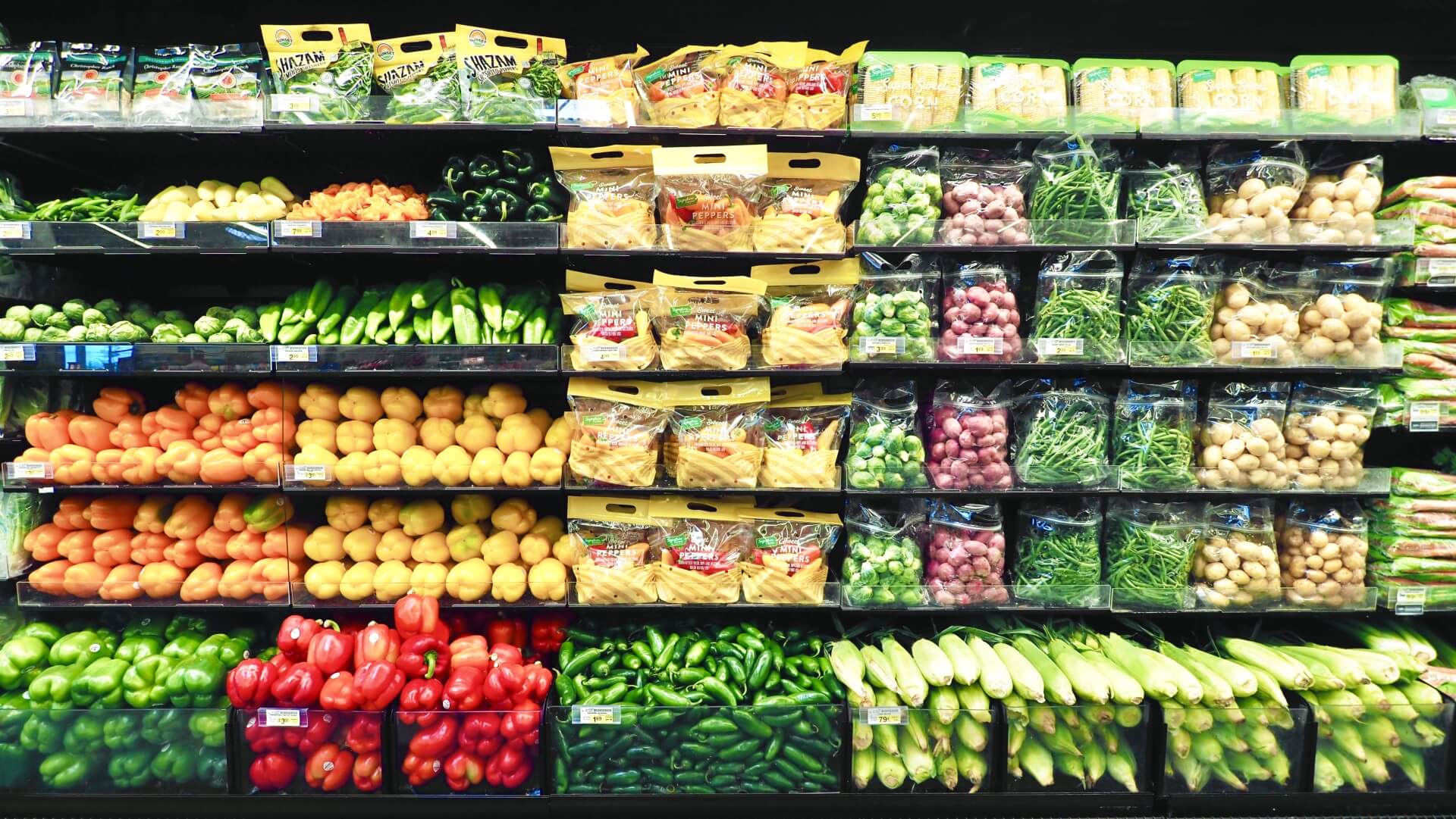 スーパーマーケットでたくさんの野菜や果物が陳列されている写真