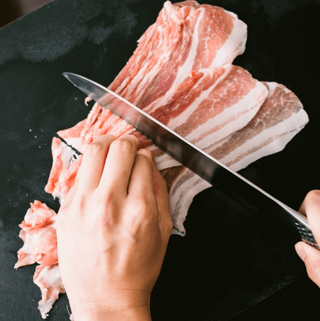 豚バラ肉を包丁で切り分ける手元の写真