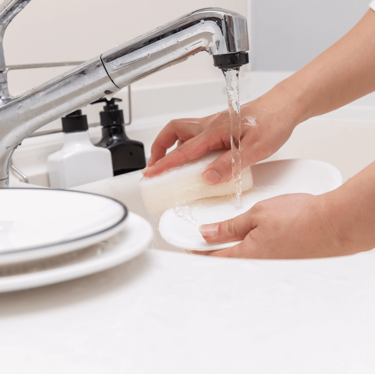 スポンジでお皿を洗う手の写真