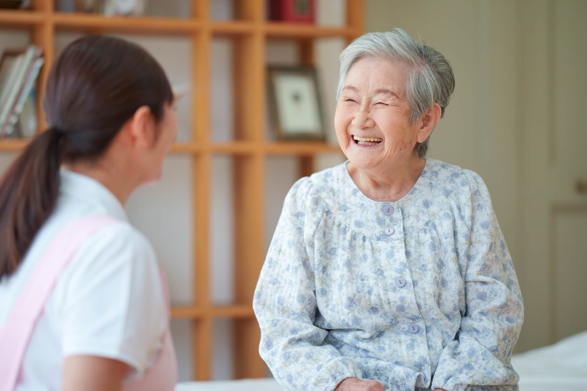 満面の笑みで女性介護スタッフと会話する高齢者女性の写真