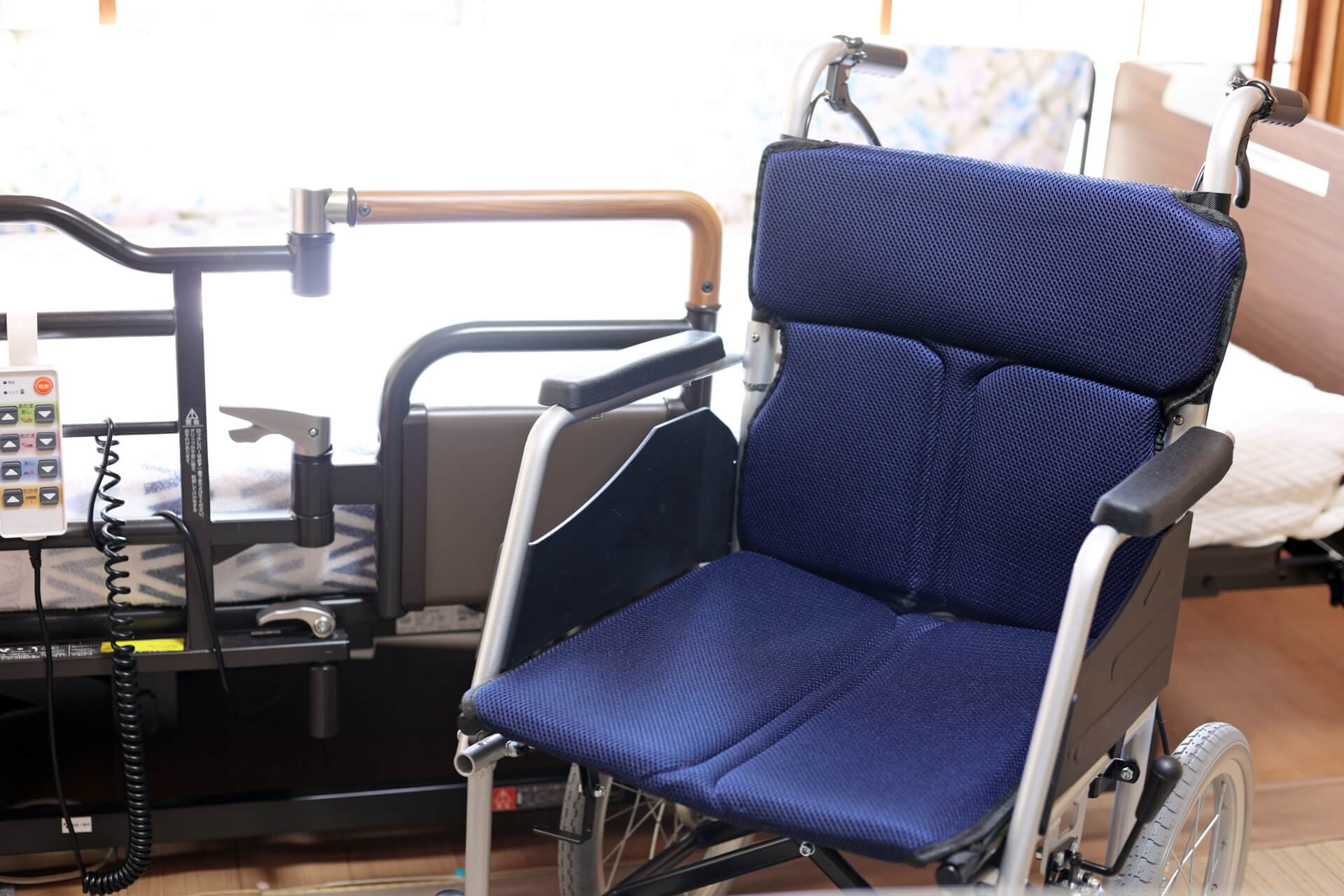 電動昇降機能などが付いた、高機能な介護用ベッドと、その手前に車椅子が置いてある写真