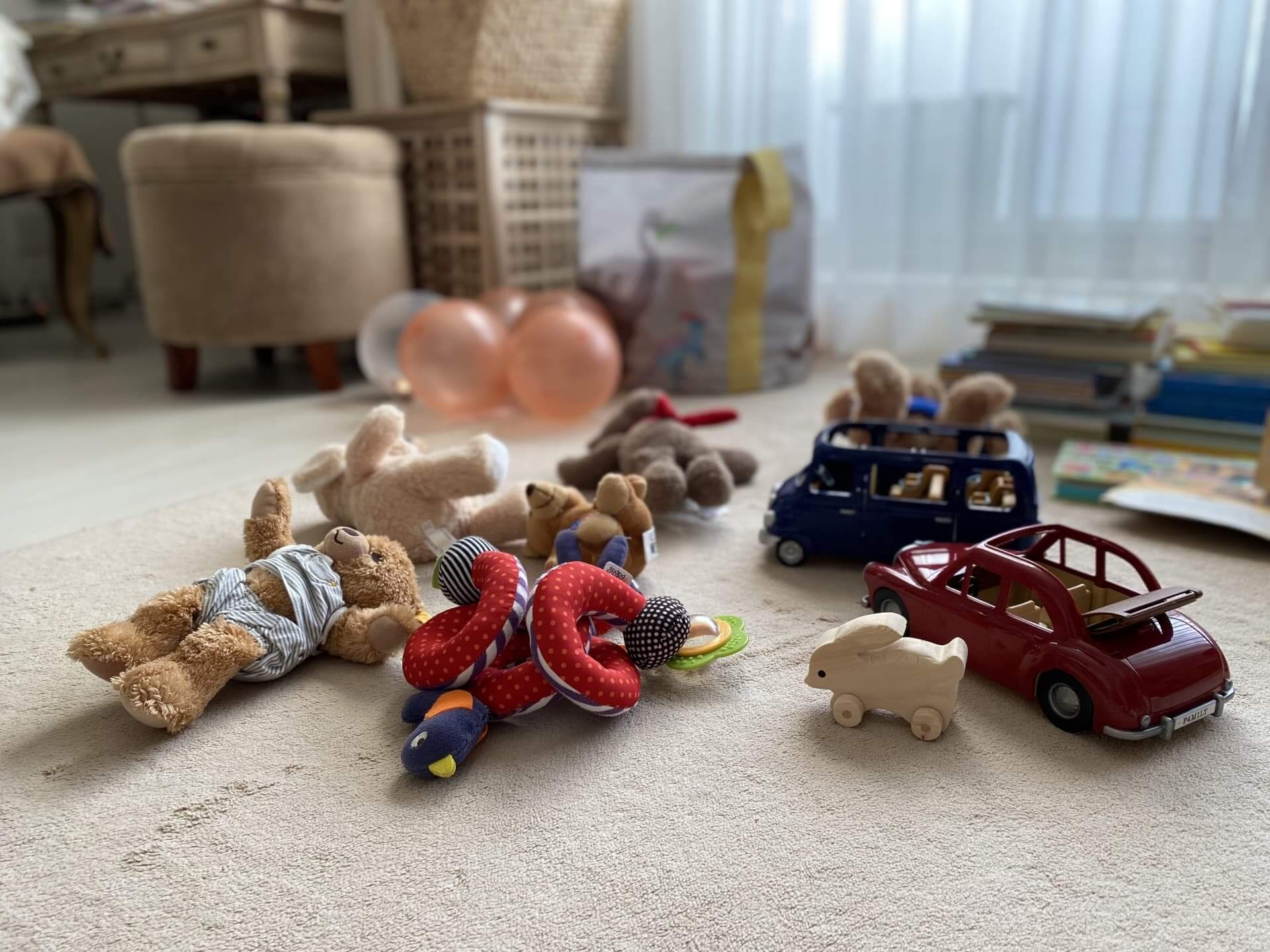 子どもが遊んだ後の玩具が床に乱雑に散らかって残っている写真