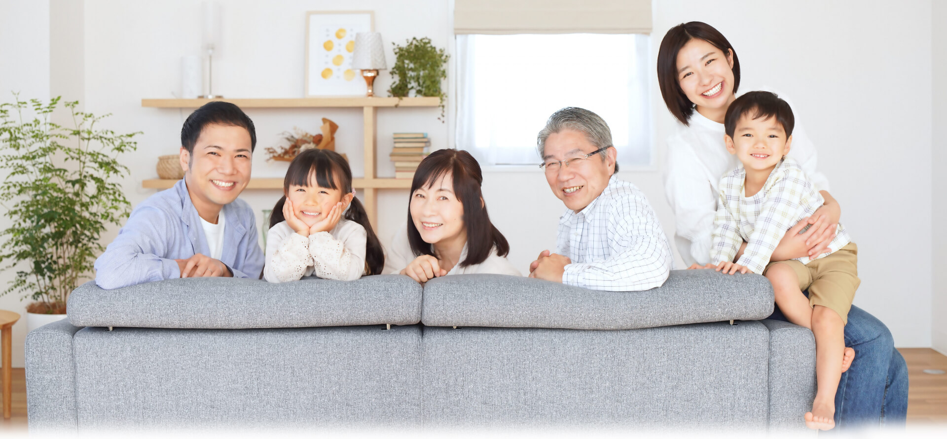 6人の家族がソファーに座り、振り向いてこちらを笑顔で見つめている写真