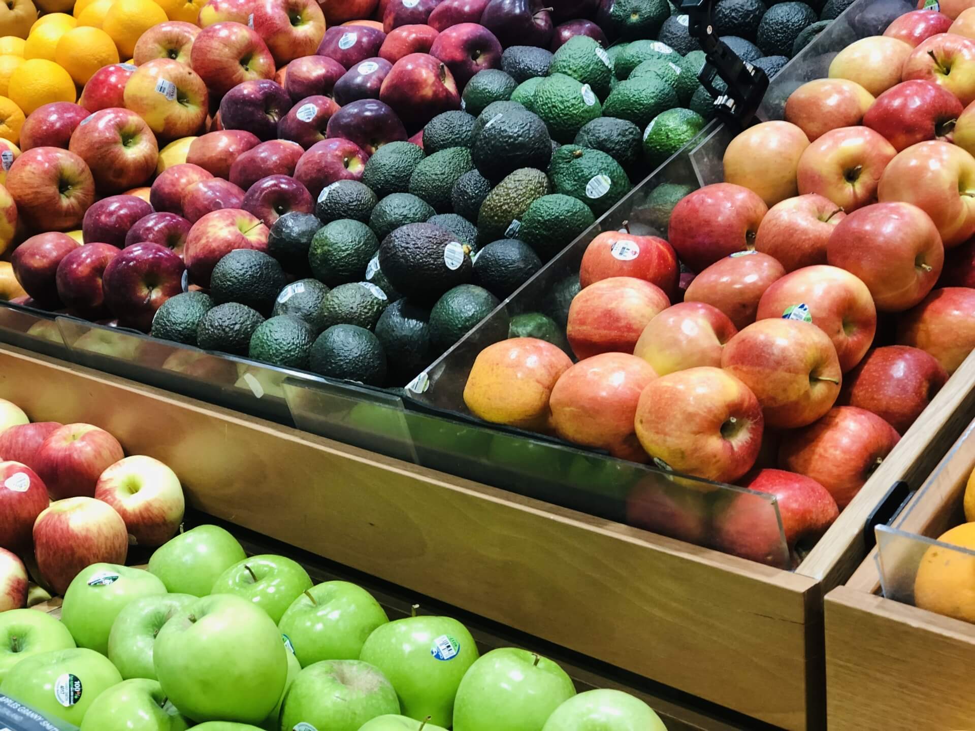 様々な種類のりんごやみかん、ゴーヤなどが陳列されたスーパーの売り場の写真